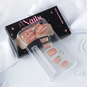 Détail de faux ongles roses élégants dans leur boîte noire avec perles et fleurs