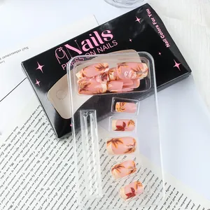 Close-up of maple leaf press-on nails with gold glitter in a black gift box