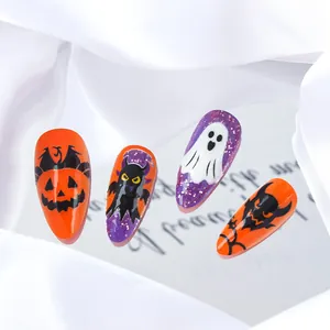 Détail de faux ongles d'Halloween avec paillettes violettes, citrouilles et fantômes