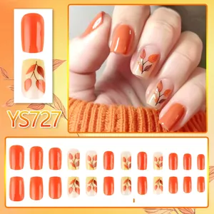 Detail view of autumn orange press-on nails with maple leaf art and glossy finish