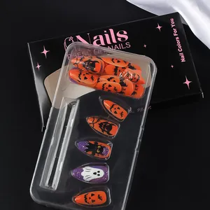 Détail macro de faux ongles d'Halloween avec motifs de fantômes et citrouilles en boîte