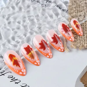 Macro shot of long almond-shaped press-on nails featuring autumn maple leaf designs