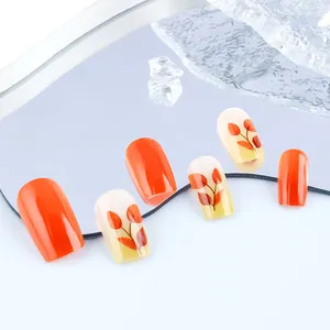 Close-up of orange-red press-on nails with maple leaf patterns and high-gloss finish
