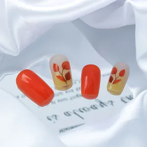 Detail of autumn maple leaf patterns and glossy orange press-on nails on white satin