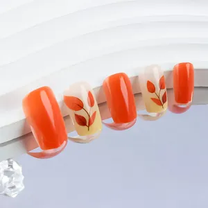 Detail of short square press-on nails with autumn maple leaf patterns and glossy orange finish