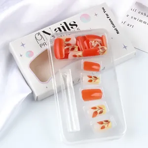 Close-up of orange and autumn leaf patterned press-on nails in elegant retail packaging