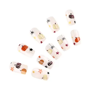 Detail of Halloween press-on nails featuring pumpkin, spider web, and star patterns