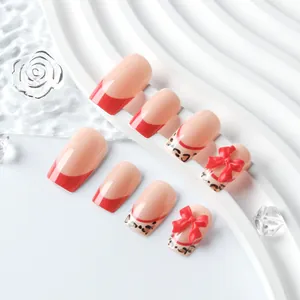 Detail of red French square press-on nails with leopard patterns and 3D bows