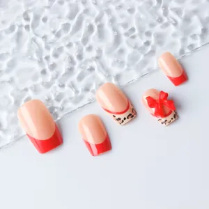 Detail of square nails with red French tips, leopard patterns, and 3D bows decorations