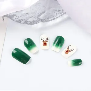 Close-up of green and white Christmas press-on nails with cartoon elk patterns and glitter