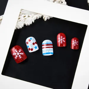 Primer plano de uñas postizas de Navidad rojas y azules con copos de nieve y purpurina