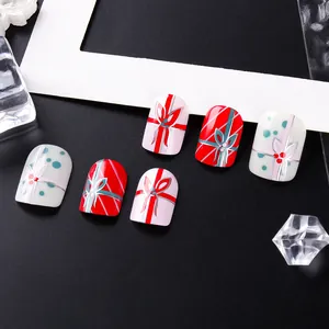 Detail of Christmas press-on nails featuring red and pink ribbons with bow designs