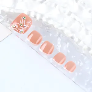 Detail of nude pink press-on toenails with white floral patterns and rhinestones