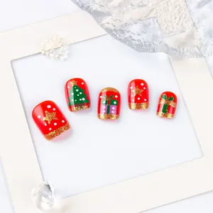 Close-up of red Christmas press-on nails featuring hand-painted trees and glitter
