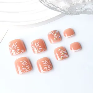 Detail of nude pink toe nails with white floral patterns and rhinestone accents