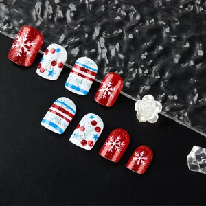 Detalle de uñas postizas cortas brillantes con patrones de copos de nieve de Navidad