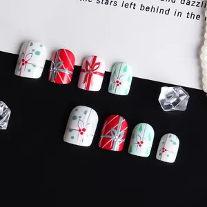 Detailed view of Christmas press-on nails with red bow designs and berry accents