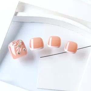 Detail of pink French press-on toenails with white floral patterns and small rhinestones