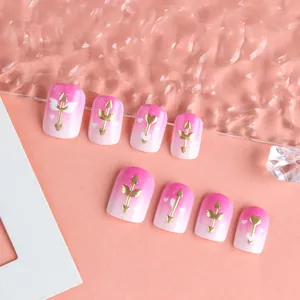 Dettagli di unghie finte sfumate rosa con frecce di Cupido dorate e cuoricini