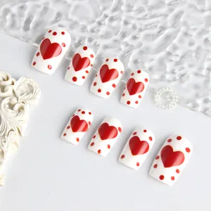 Detail of red heart patterns on white square press-on nails set with glossy finish