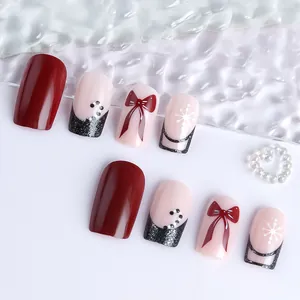 Close-up of red Christmas press-on nails with bow designs and white snowflake patterns