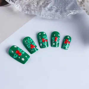 Détail des faux ongles de Noël verts avec baies rouges et feuilles en relief 3D