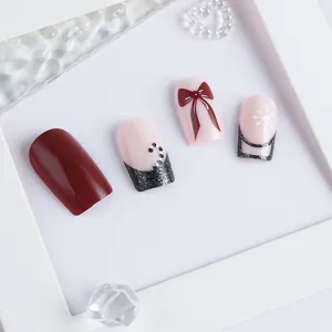 Detail of red bow and white snowflake patterns on elegant festive press-on nails