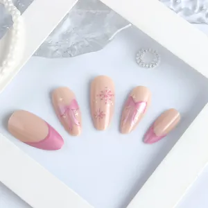 Detail of pink almond fake nails with snowflake patterns and French bow designs