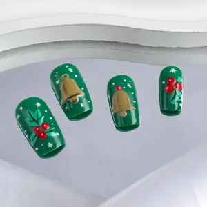 Vue détaillée de faux ongles de Noël verts avec motifs de cloche et baies de houx