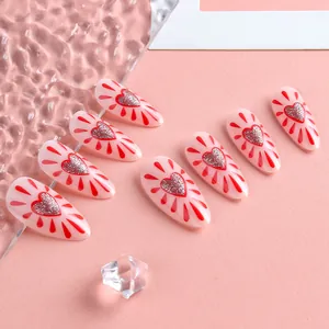 Macro shot of almond-shaped press-on nails with red glitter hearts and radiant lines
