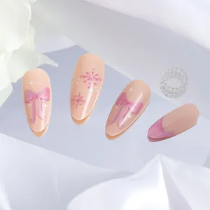 Detail of pink almond fake nails featuring hand-painted snowflakes and bows on a mirror