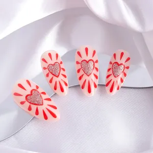 Detail of almond press-on nails featuring red hearts and silver glitter on pink base