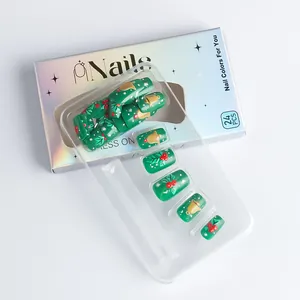 Détail de faux ongles de Noël verts avec cloches dorées en 3D et motifs festifs de flocons