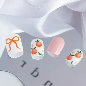 Detail of short square press-on nails with bow designs and fresh fruit patterns