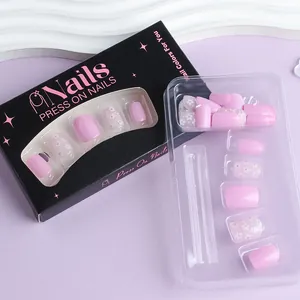 Detail of pink floral press-on nails with glossy finish and delicate rhinestones in packaging