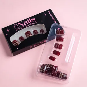 Dettaglio di unghie natalizie bordeaux con fiocchi di neve bianchi e confezione regalo