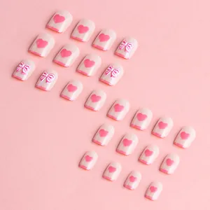 Short square press-on nails with pink French tips, 3D bows, and heart patterns
