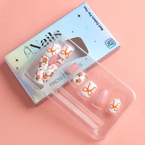 Detail of short square press-on nails with pink bow and peach floral patterns