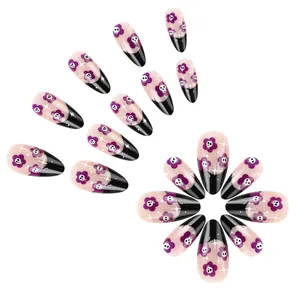 Detail of Halloween press-on nails featuring purple flowers and skulls on black French tips
