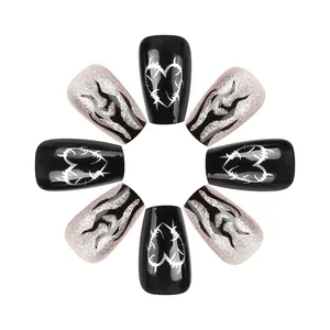 Detail of coffin-shaped press-on nails with black flame and silver barbed heart designs