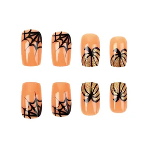 Detail of short pumpkin press-on nails with spider web patterns and gold glitter for Halloween