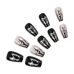 Detail of coffin shape press-on nails with black heart thorns and pink glitter flames