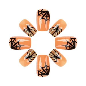 Detailed close-up of glossy orange Halloween nails with spider web and pumpkin glitter