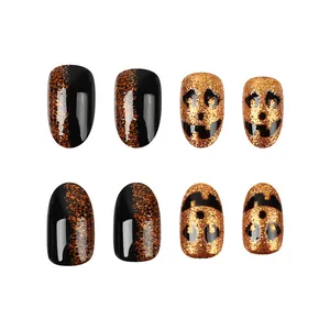 Detail of short round Halloween press-on nails with pumpkin faces and orange glitter