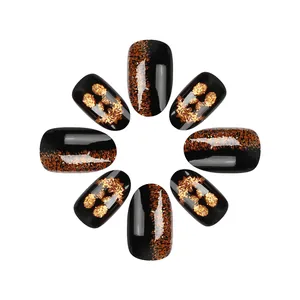 Detail of glossy black Halloween nails with glitter pumpkin and skull patterns