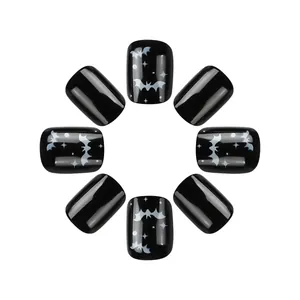 Detail of short glossy black press-on nails with white bat and star Halloween patterns