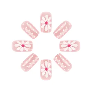 Close-up of pink press-on nails with white daisy patterns and polka dots on square tips