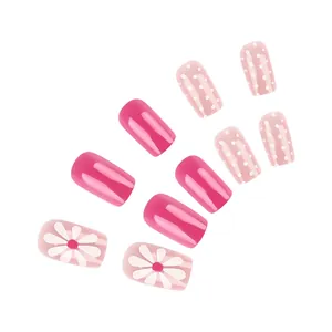 Detailed view of short square press-on nails with daisy patterns and pink polka dots