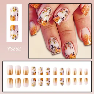 Short glossy French press-on nails featuring autumn pumpkin and gold glitter design