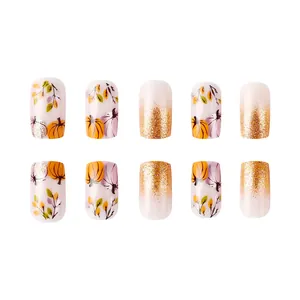 Short glossy press-on nails with autumn pumpkin designs and gold glitter accents